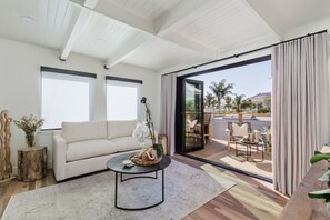A modern living room with a sofa, coffee table, and a view of the outdoors through large sliding glass doors.