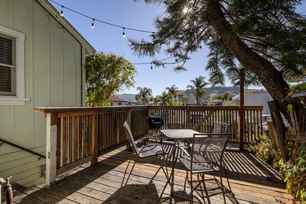 Une terrasse dotée de mobilier d’extérieur, d’un barbecue et offrant une vue sur les palmiers et les montagnes.