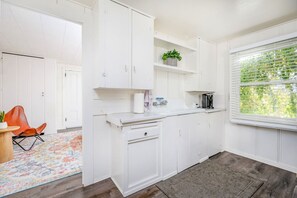 Eine Küche mit weißen Schränken, einer Kaffeemaschine und einem Fenster mit Jalousien.