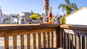 Eine Holzterrasse mit Tisch, einer Weinflasche und Gläsern.
