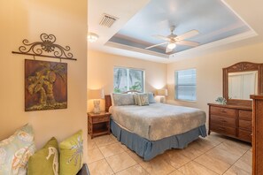 A bedroom with a bed, nightstands, a dresser, a ceiling fan, and a wall-mounted artwork. - Blue Starfish (Fort Myers Beach)