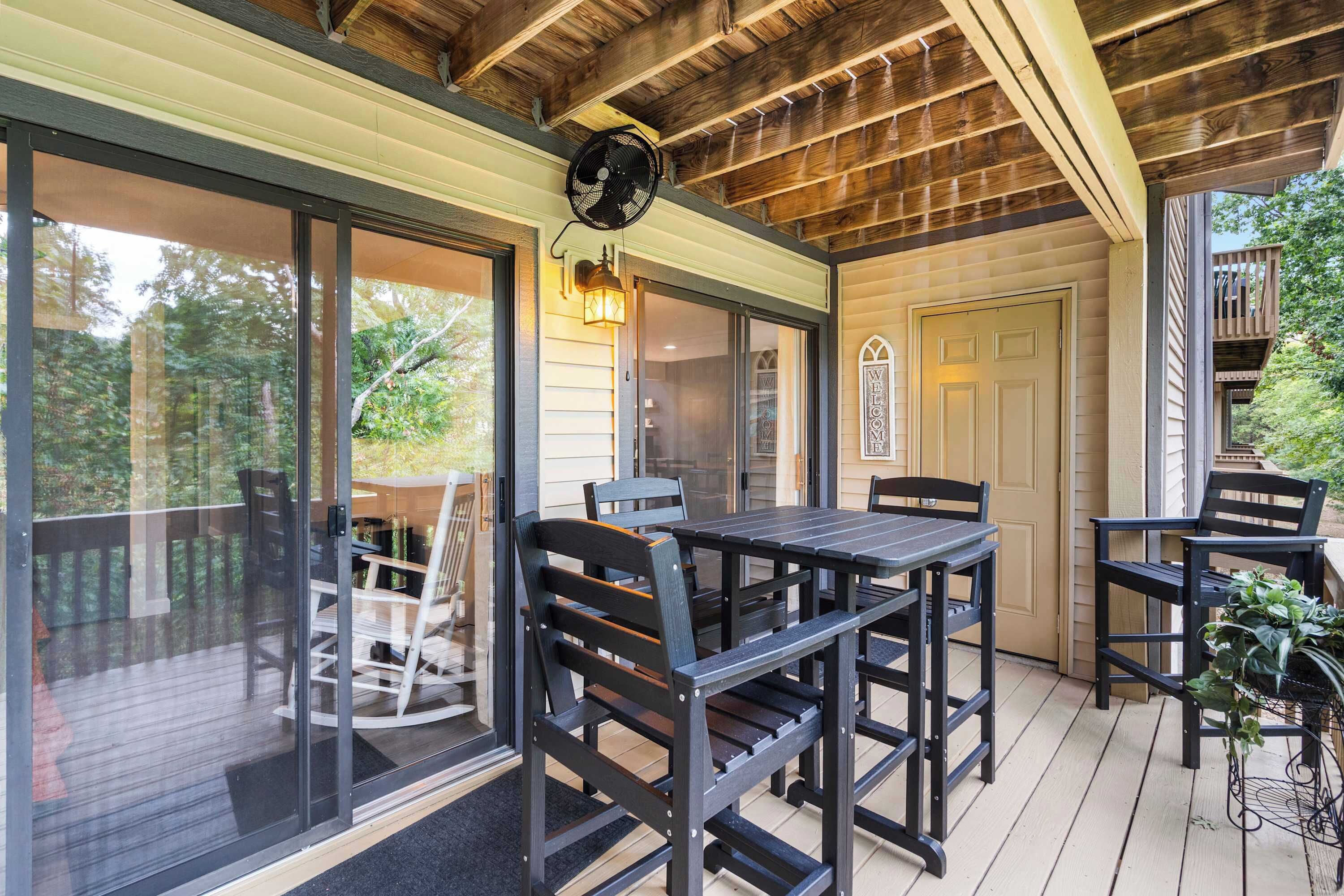 Een overdekt terras met houten plafond, een tafel en stoelen, en een schuifdeur die uitkomt op een terras.