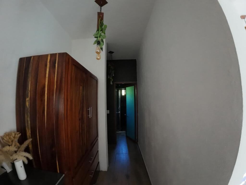 A narrow hallway with a wooden cabinet on the left and a door at the end.