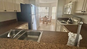 Una cocina con encimeras de granito, electrodomésticos de acero inoxidable y una zona de comedor con mesa y sillas.