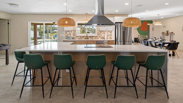 A modern kitchen with a central island, bar stools, pendant lights, and stainless steel appliances. - Private Heated Pool/Waterfront/5-mins to Beach (Largo)