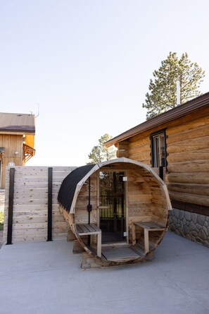 A log cabin with a barrel-shaped entrance, a wooden exterior, and a stone wall. - Canyon Hideout at Devils Tower (Moorcroft)