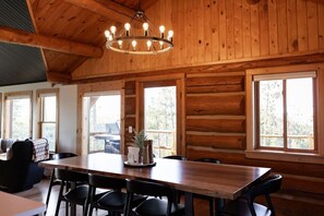 Un interior de madera con una mesa de comedor, sillas y una lámpara de araña.