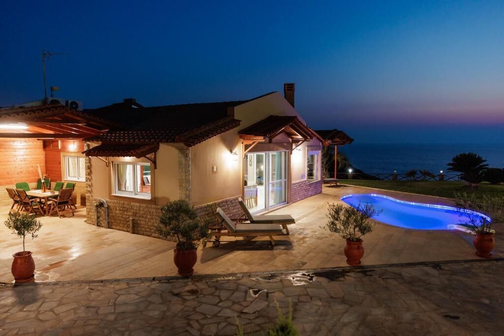 A house with a swimming pool, outdoor seating, and a view of the sea.
