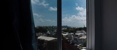 Una ventana con vistas a un paisaje urbano, que incluye edificios y un cielo despejado.