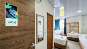 Ein Hotelzimmer mit zwei Einzelbetten, einem Holzschrank, einem Spiegel und einem gerahmten Bild an der Wand.