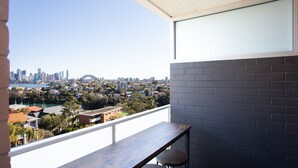 A balcony with a view of a city skyline, including a bridge and buildings.