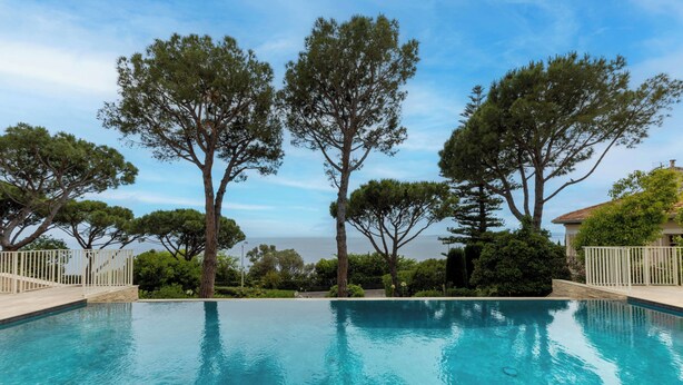 A clear blue pool surrounded by trees and a view of the sea. - Superb apartment with exceptional sea view (Nice)