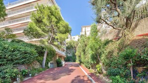 A narrow street flanked by lush greenery and residential buildings. - Superb apartment with exceptional sea view (Nice)