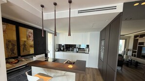 A modern kitchen with a central island, pendant lighting, and a view of the living area. - Superb apartment with exceptional sea view (Nice)