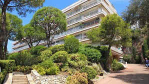 A multi-story hotel with balconies, surrounded by lush greenery and trees. - Superb apartment with exceptional sea view (Nice)