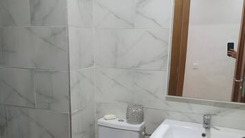 Chuveiro, toalhas de banho, sabonete, papel higiênico