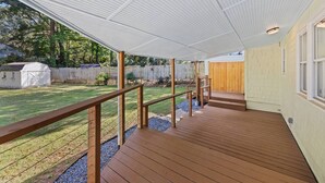 A covered outdoor deck with wooden railings, a wooden staircase, and a view of a backyard with a fenced area and a shed. - Chef's Kitchen; 2 King Beds with 55" TV's & Bunk Bed, 70" TV in Living Room (Atlanta)