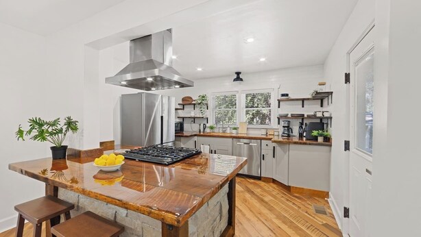 A modern kitchen with a central island, stainless steel appliances, and wooden flooring. - Chef's Kitchen; 2 King Beds with 55" TV's & Bunk Bed, 70" TV in Living Room (Atlanta)