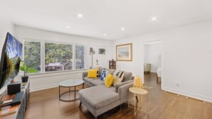 A modern living room with a grey sofa, a coffee table, and a TV on a stand. - Chef's Kitchen; 2 King Beds with 55" TV's & Bunk Bed, 70" TV in Living Room (Atlanta)