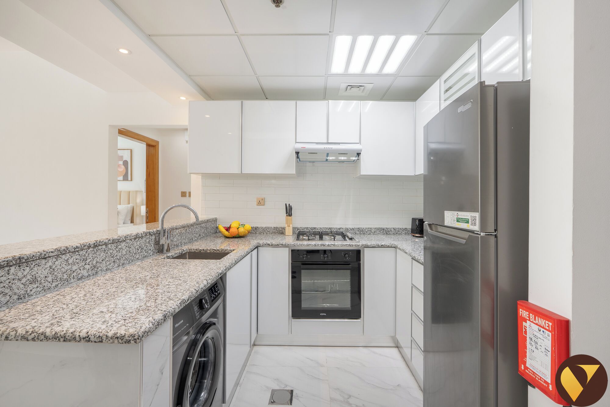 Een moderne keuken met witte kastjes, een roestvrijstalen koelkast, een inbouwoven en een wasmachine.