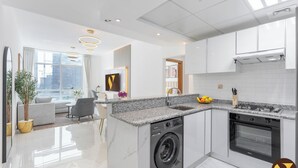Une cuisine moderne dotée d’un lave-linge et d’un four intégrés, d’un plan de travail en granit et offrant une vue sur la ville grâce à de grandes fenêtres.