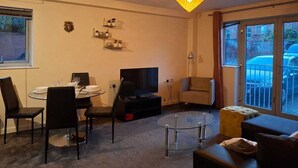 A living room with a dining area, a TV, a sofa, and a balcony with a car.