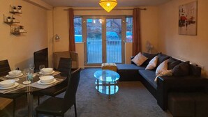 A living room with a dining area, a glass coffee table, a sofa, and a balcony with a view.