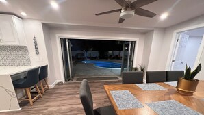 Un coin repas avec une table en bois, des chaises noires et un ventilateur de plafond.