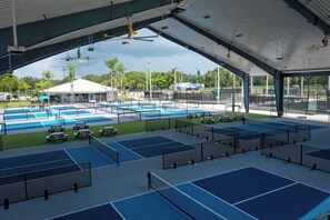 An indoor tennis court complex with multiple courts, seating areas, and a covered spectator section.