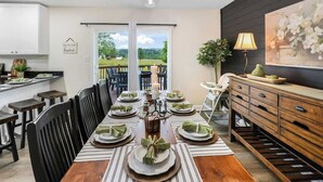 A dining area with a long table set for six, a chandelier, and a view through a glass door. - Sauna, Theatre, Game Room, Gym, EV Chrger, Firepit (Toms Brook)
