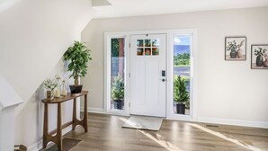 A hallway with a wooden bench, a potted plant, a white door with glass panels, and a small mat at the entrance. - Sauna, Theatre, Game Room, Gym, EV Chrger, Firepit (Toms Brook)