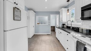 Una cocina moderna con armarios blancos, encimera negra y microondas integrado.