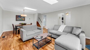 Una sala de estar moderna con dos sofás grises, una mesa de centro de madera y un comedor con una mesa y sillas.