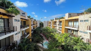 Un resort con edificios de varios pisos, un patio central con piscina y abundante vegetación.