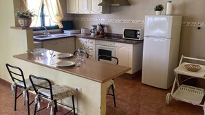 Una cocina pequeña con comedor, refrigerador, microondas y pileta.