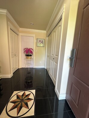 A hallway with a polished black floor, white doors, and a framed picture on the wall. - Bright West Side Retreat • 3BR • Kitchen & Living (Vancouver)