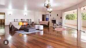 Amplia sala de estar con piso de madera, un juego de sofá, televisor y chimenea.
