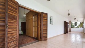 Un pasillo amplio con puertas de madera y suelo de baldosas.