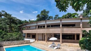 Un edificio de dos pisos con piscina, zona de estar al aire libre y un patio cubierto.
