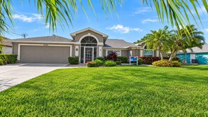 Palm trees and a neatly landscaped front lawn frame the villa's welcoming entrance.