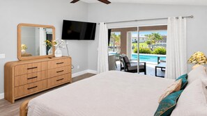 Wake up to a pool view in this bedroom, with terrace access, a wall-mounted TV, and a dresser for your belongings.