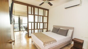 A bedroom with a bed, a wooden partition, a ceiling fan, and a view of a balcony. - Ipana by The Spot Rentals (Playa del Carmen)