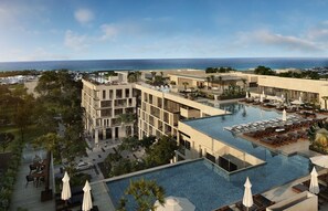 Un hotel moderno con piscina en la azotea, varios balcones y vistas al océano.