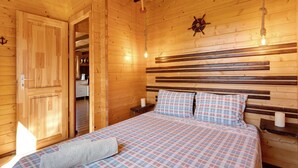 A wooden cabin room with a bed, a wooden headboard, a hanging light fixture, and a starfish decoration on the wall. - Cabin 'Pátio do Pescador' with Private Terrace, Private Garden, and Wi-Fi (Peniche)