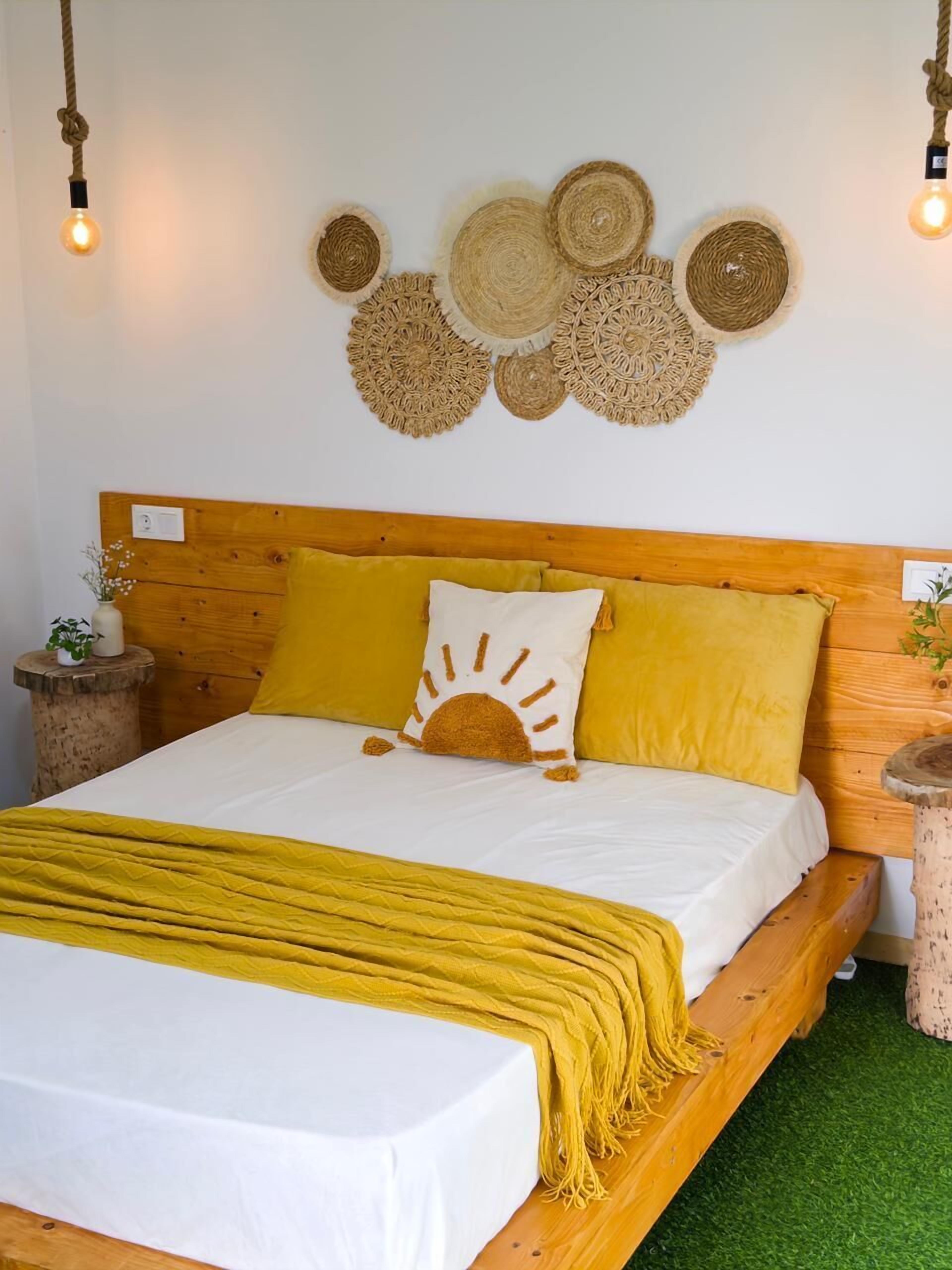 A bed with a wooden headboard, yellow bedding, and a white throw blanket.