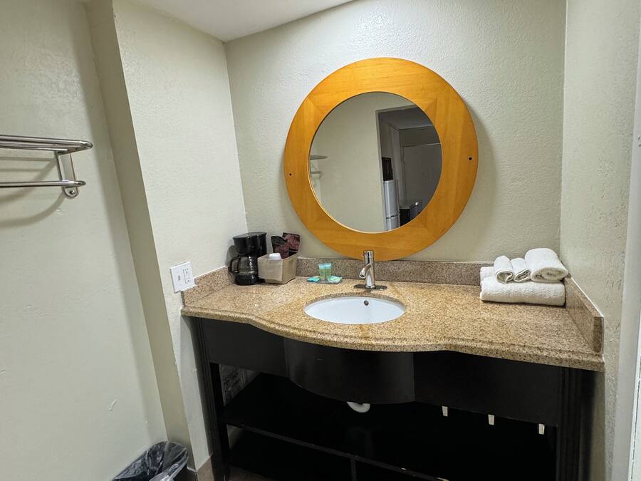 Une salle de bain avec un miroir rond, un lavabo et un porte-serviettes.