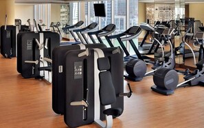Une salle de sport équipée de divers appareils d’exercice, dotée de grandes fenêtres et présentant un aménagement intérieur moderne.