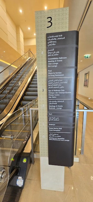 A vertical sign with a list of amenities and locations, including a club lounge, fitness center, and hotel reception.