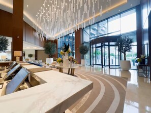 A modern lobby with a marble reception desk, large windows, and a rotating door.