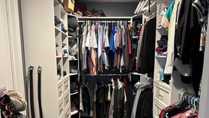 Un armario vestidor con ropa colgada, estantes y un otoman para guardar objetos.